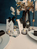 Decorative table setting for two with candles, flowers, and cards on a dark blue background