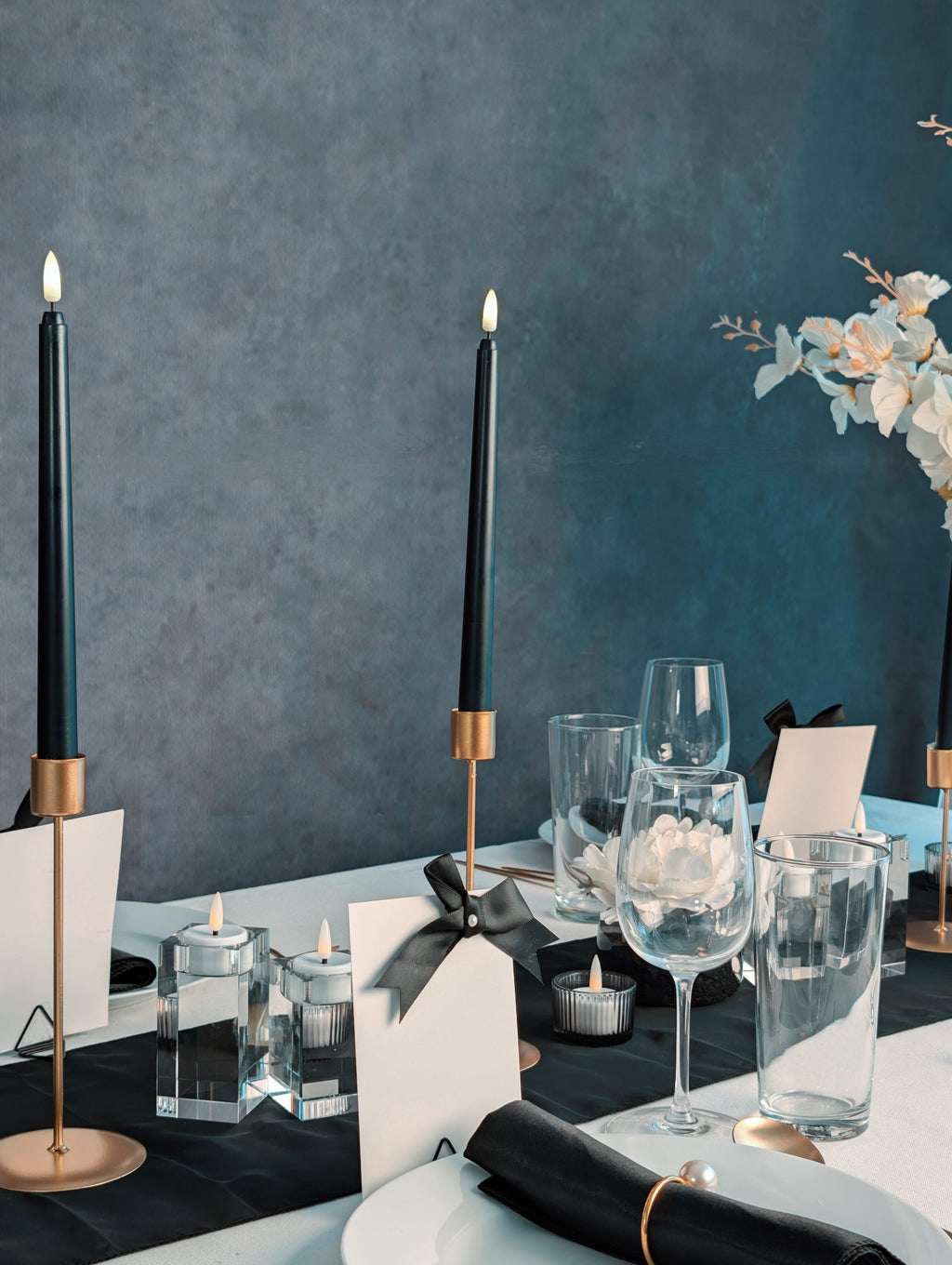 Elegant black and white table setting with black candles, glasses, and decorative elements.