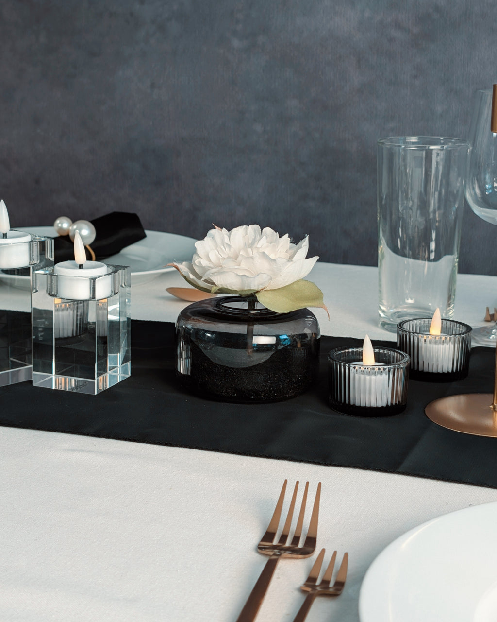 Elegant table setting with black and white decor, including candles and a flower.
