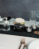 Elegant table setting with black and white decor, including candles and a flower.