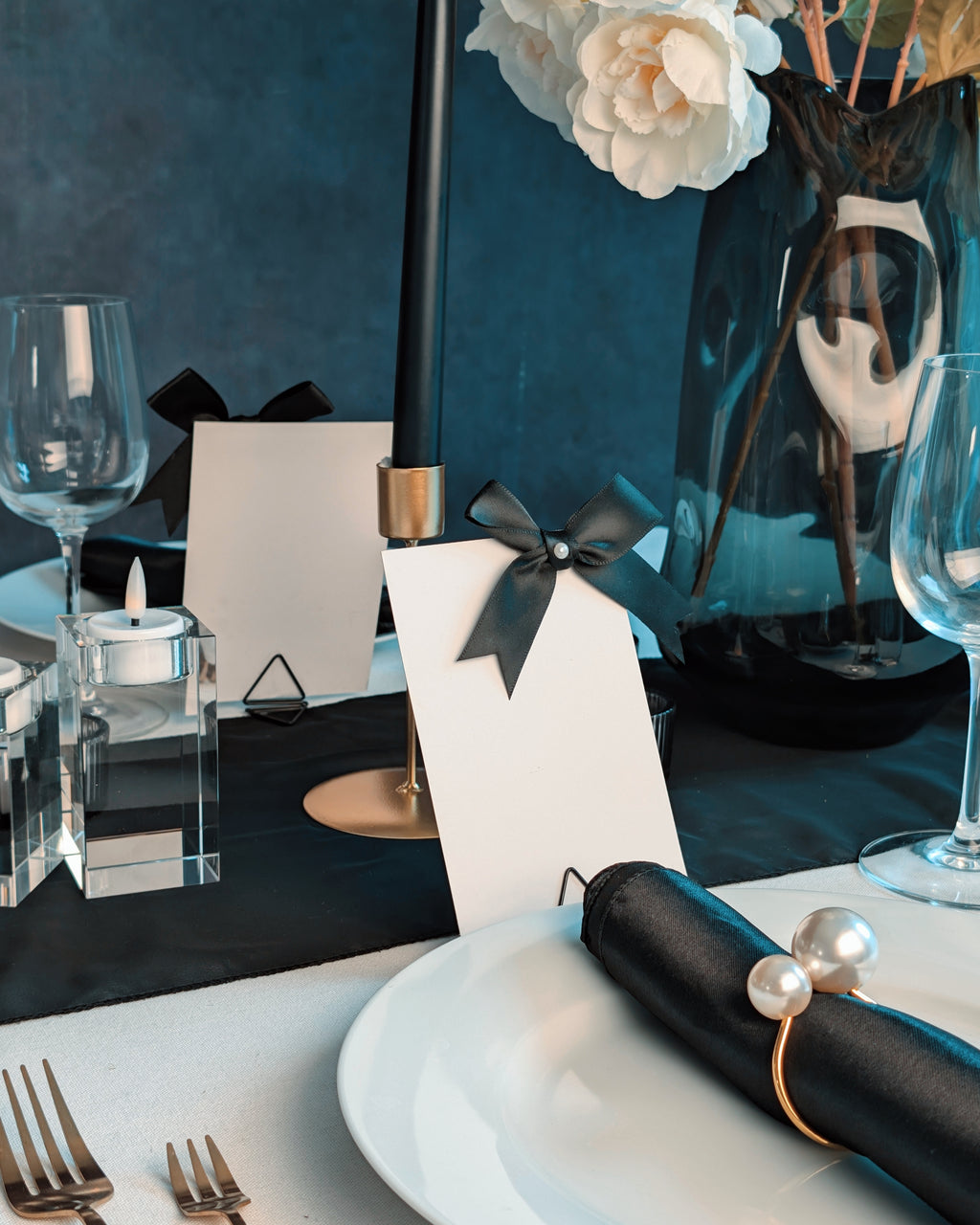 Decorative table setting with black and white elements, including a candle holder and napkin.