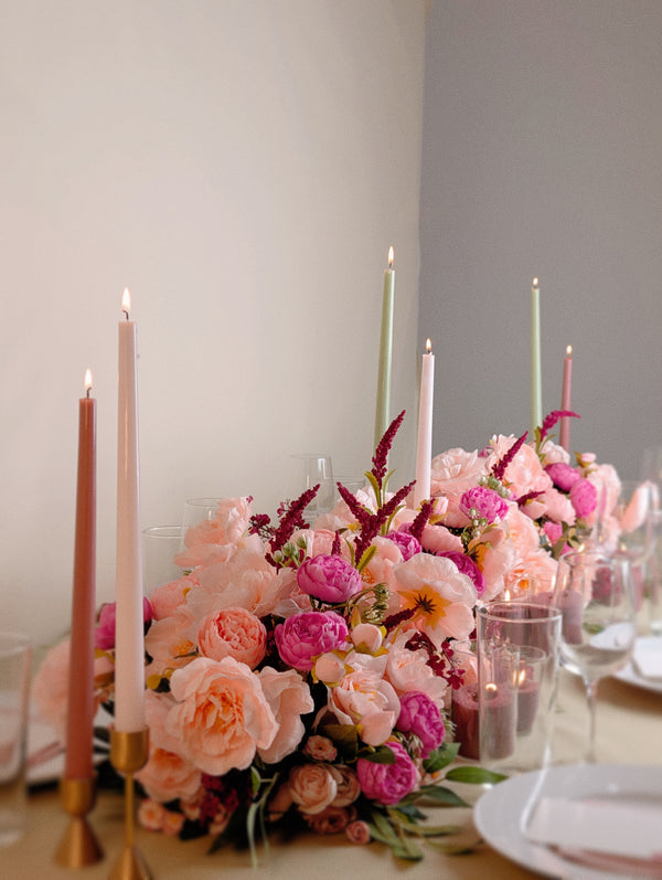 Decorative floral arrangement with candles on a table setting.