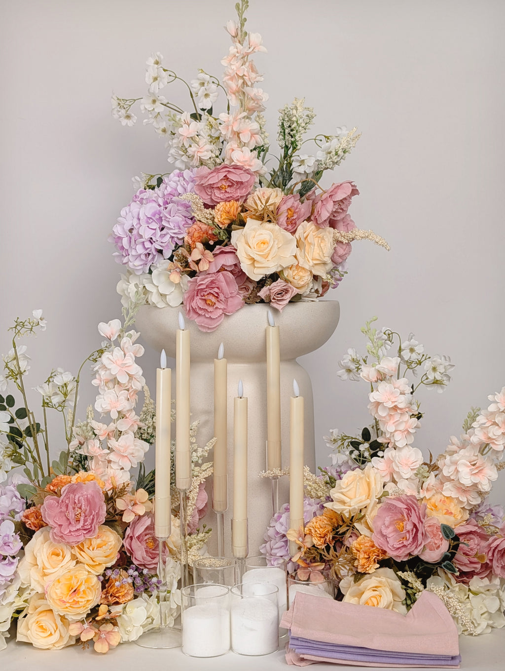 Decorative setup with flowers and candles on a gray background