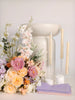 Floral arrangement with candles and a white candle holder on a light background