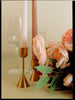 Decorative setup with candles, glasses, and flowers on a neutral background